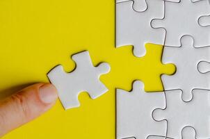 Top view of hand connecting a white jigsaw puzzle into its original position. Solution concept photo