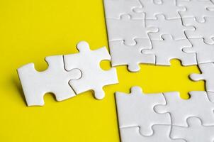 Close up view of missing white jigsaw puzzles, symbolizing partnership and unity on yellow background photo