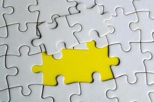 Top view of missing white jigsaw puzzles, symbolizing partnership and unity on yellow background photo