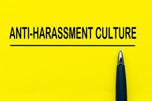 Anti-harassment culture text on yellow lines with pen representing a proactive stance for behavioral change photo