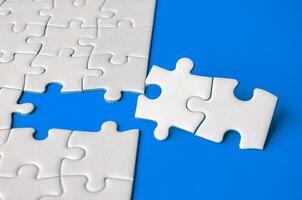 Close up view of missing white jigsaw puzzles, symbol of partnership and unity on blue background photo
