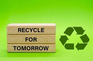 Recycle symbol with wooden blocks with text Recycle For Tomorrow on a green background. Promoting reuse, reduce, and recycle for sustainability. photo