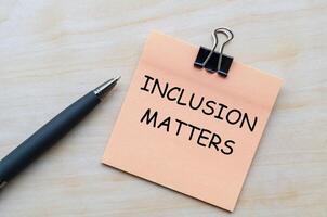 Inclusion matters text on pink notepad representing the importance of diversity and belonging in all spaces.. photo