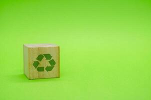Recycle symbol with wooden blocks on green background. Promoting reuse, reduce, and recycle for sustainability. photo