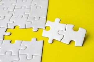 Close up view of missing white jigsaw puzzles, symbol of partnership and unity on yellow background photo
