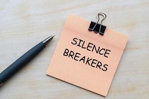 Silence breakers text on pink notepad representing courage to speak up and challenge harassment. photo