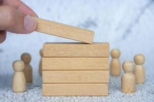 Hand placing wooden blocks with customizable space for text or ideas with wooden dolls background. Copy space concept photo