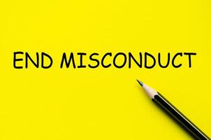 End misconduct text on yellow pad with pen representing the enforcement of integrity and accountability. photo