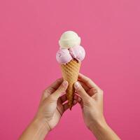 Delightful ice cream cone presentation held against a solid rose-pink backdrop photo