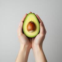 Hands gently cradling a vibrant avocado half, displaying the pit's rich texture photo