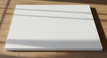 Minimalist blank white canvas on a wooden surface with soft shadows cast by sunlight photo