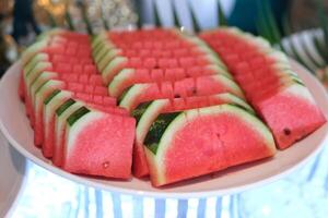 A fresh and vibrant plate of sliced watermelon wedges, showcasing the juicy red flesh and crisp green rind. The bright colors and natural textures make it a perfect choice for health food lovers. photo