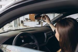 Customer Adjusting Rearview Mirror in New Car at Dealership photo