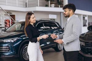 Salesperson giving car key to customer in a dealership photo