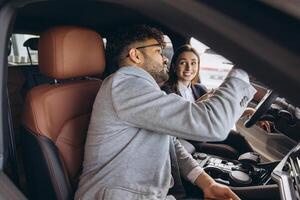 Car salesman showing new vehicle to customer at dealership photo