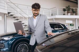 Car Salesman Showing a New Car to a Customer While Holding a Laptop photo