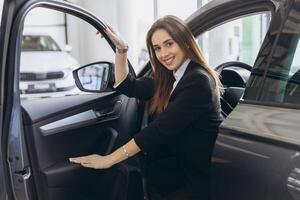 Saleswoman inviting customer to enter new car at dealership photo