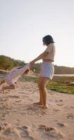 Mother spins with her little daughter on tropical sandy beach. Beautiful family on coastline video