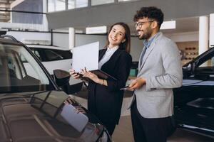 Salespeople showing new car to potential customer at dealership photo