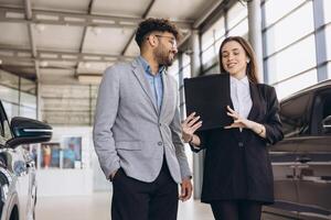 Car salesperson showing new vehicle to customer in dealership photo