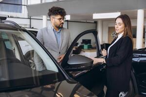 Car dealer showing new vehicle to customer in a showroom photo