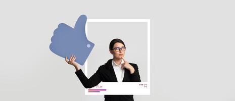 A woman in professional attire thoughtfully poses with a large thumbs-up symbol. She stands in front of a minimalist backdrop, symbolizing online engagement and content sharing. photo