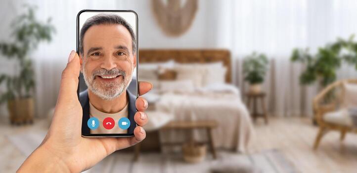 A person has a call on their smartphone while sitting in a comfortable home setting. The room features plants and a warm atmosphere, making communication enjoyable. photo