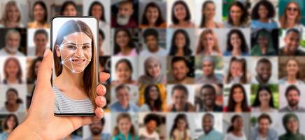A person holds a smartphone that shows a face scan on the screen against a backdrop of diverse faces. This highlights the advancement in identification technology in modern society. photo
