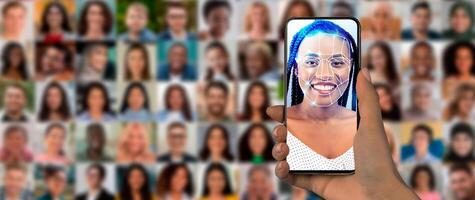 A person holds a smartphone displaying a face scan against a backdrop of diverse portraits. This showcases the advanced technology used for facial recognition in daily life. photo