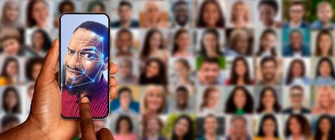 A person holds a smartphone displaying facial recognition technology on the screen. The background is a collage of diverse faces, highlighting the advancements in identification methods. photo