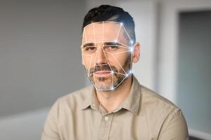 A man with a neutral expression sits for a facial recognition check. The technology overlays geometric shapes on his face, illustrating advanced identification practices in contemporary settings. photo