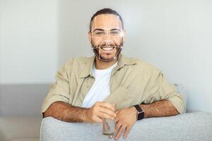 A person comfortably sits on a couch, enjoying a drink while engaging with facial recognition technology. The atmosphere reflects a blend of relaxation and innovation in personal identification. photo