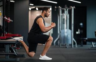 Portrait Of Athletic Black Man Making Bulgarian Split Squat Exercise At Gym, Motivated Young African American Male Training On Leg Muscles At Modern Sport Club, Enjoying Bodybuilding, Side View photo