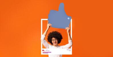A joyful influencer is holding a large thumbs up sign against a bright orange background. This engaging display highlights the positive aspects of social media interaction and content creation. photo