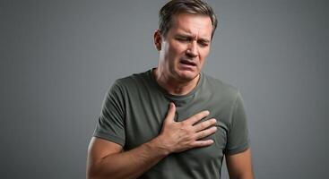 Man with chest pain on gray background photo