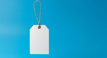 Blank white price tag hanging on a string on a blue background photo