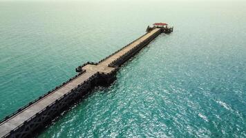 Aerial View of a Long Wooden Pier Extending into the Turquoise Ocean Under a Clear Sky photo