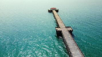 Aerial View of a Long Wooden Pier Extending into the Turquoise Ocean on a Sunny Day with Clear Blue Skies photo
