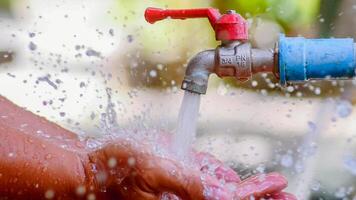 Close-Up of Hands Washing Under Running Water from Outdoor Faucet with Splashing Droplets in Daylight photo