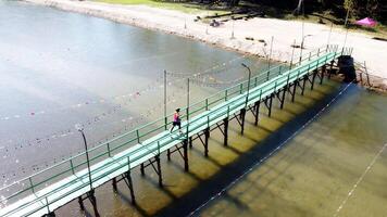 Aerial View of a Vibrant Green Bridge Over Serene Waters with Colorful Decorations and a Lone Walker photo