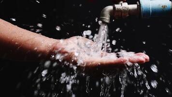 Close-Up of Water Flowing from Faucet onto Hands Against Dark Background, Highlighting Cleanliness and Hygiene photo