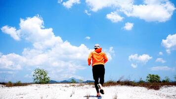 Man Running on Sandy Terrain Under Bright Blue Sky with Fluffy Clouds on a Sunny Day photo