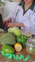A nutritionist doctor works at a table, types text on a laptop keyboard and communicates with patients, makes a meal plan and diet. The concept of health and diet, clinic, wellness. video