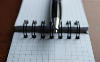 Macro Shot Of Ballpoint Pen Lying On A Bound Paper Notebook photo