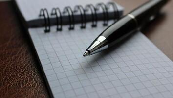 White Pages Of Spiral Address Book And Opened Ball Pen On Leather Table photo