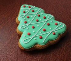 Traditional Christmas Tree Cookie Covered With Green Icing And Sweet Decor On Leather Surface Angle View photo