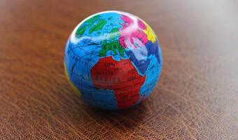 Model of Earth sphere with major transport routes between continents mapped on leather table photo