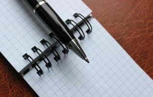 Business Pen On A Binder Of Checkered Note On A Leather Folder photo