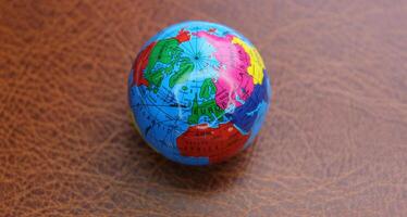 Miniature globe on a leather surface with conventionally drawn continents photo