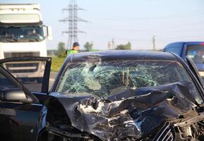 The mangled front part of a car after a head-on crash accident with a truck photo